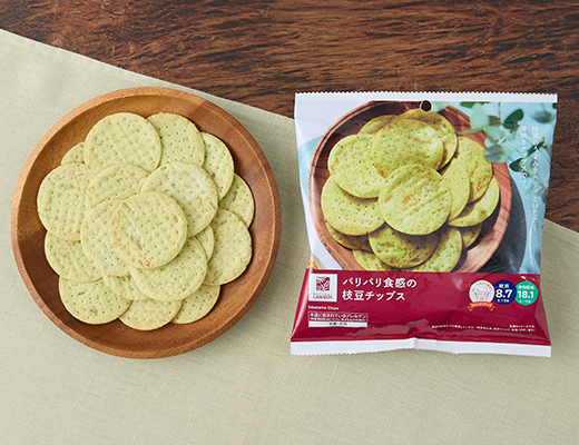 ローソン公式商品画像。木の皿に盛った枝豆チップスとパッケージ正面